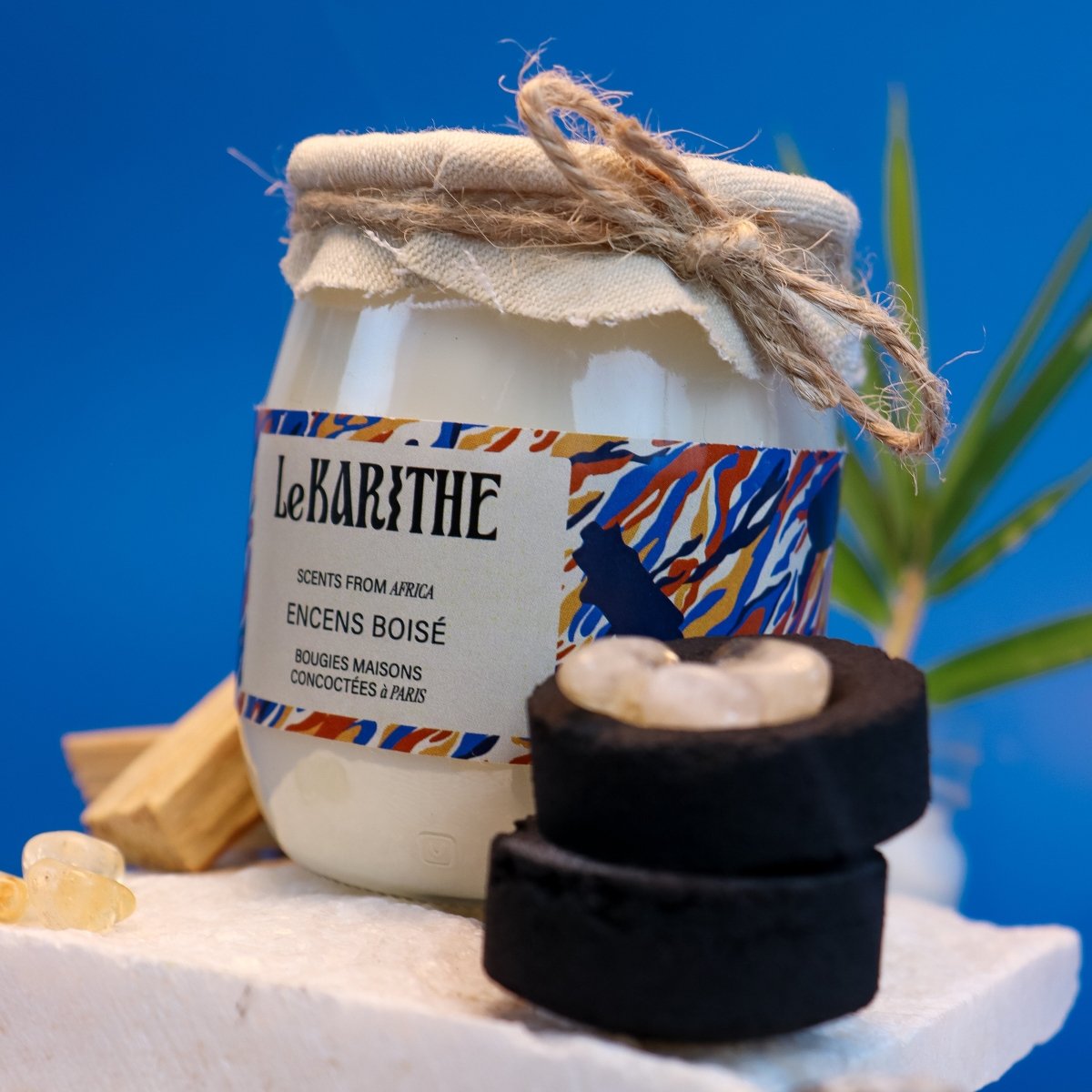 Bougie parfumée aux senteurs d'encens boisé (Thiouraye, encens sénégalais), aux ingrédients sains et simples, sur fond bleu.
