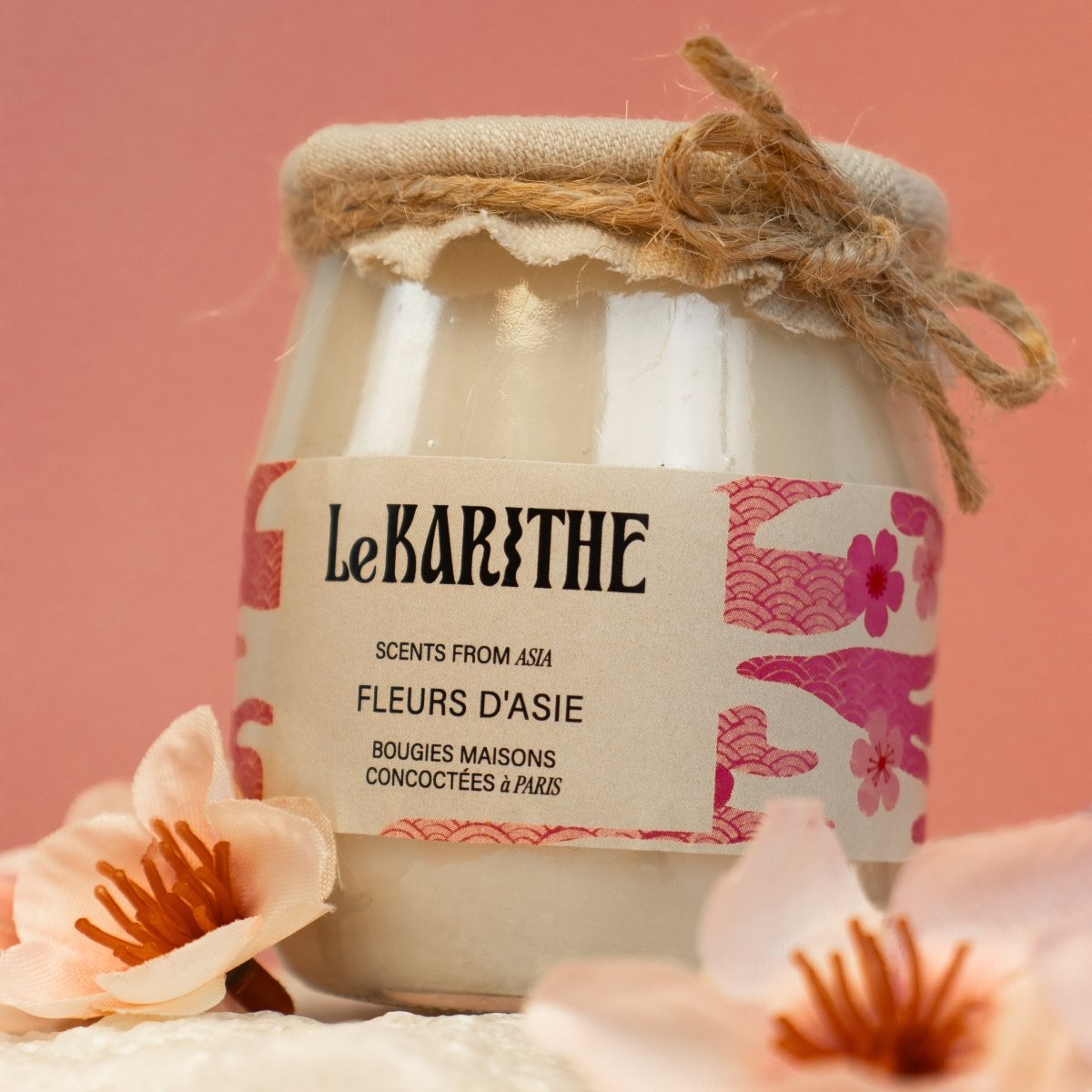 Bougie parfumée aux senteurs de fleurs d'Asie (fleur de cerisier Sakura), aux ingrédients sains et simples, présentées sur fond rose.